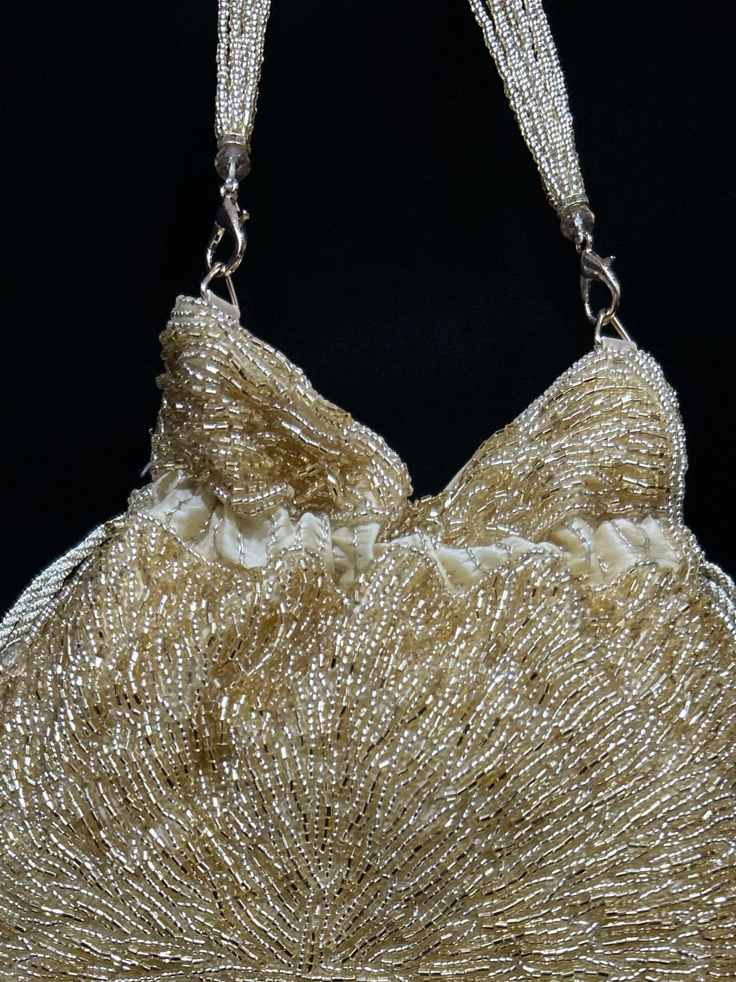 Gold beaded handbag with fringe on a black background